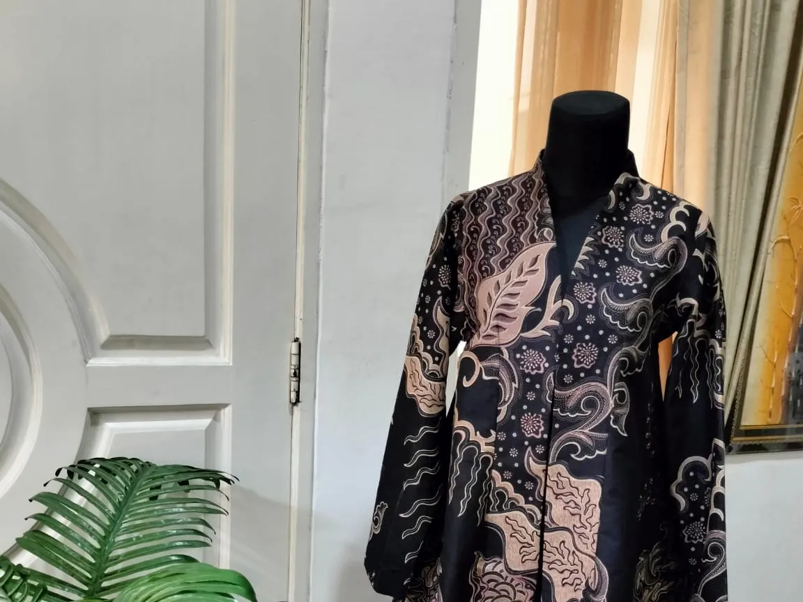 Atasan batik hitam potongan asimetris di manekin