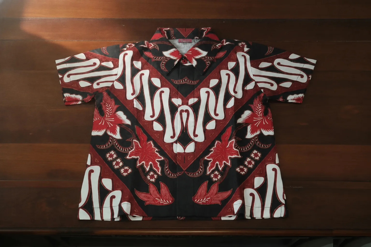Kemeja batik karya SiJahit terbentang utuh di atas meja kayu walnut